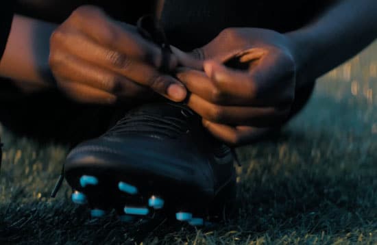 Person tying a soccer cleat.